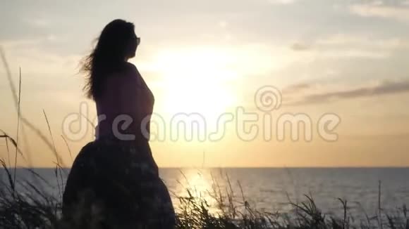 一个年轻的女孩站在海边看着美丽的日落4K3840x2160高清高清视频的预览图