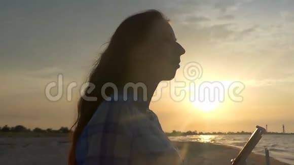 年轻女子在日落时保持着飞行无人机的控制面板视频的预览图
