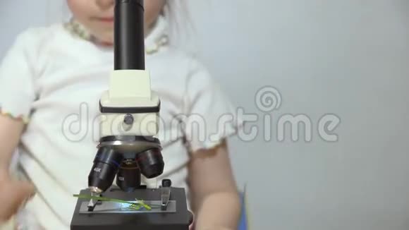 一个小女孩正在白墙旁边玩显微镜视频的预览图