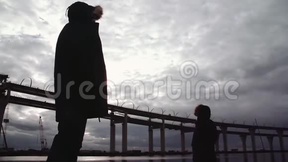 两个人的身影站在河岸上公路桥视频的预览图