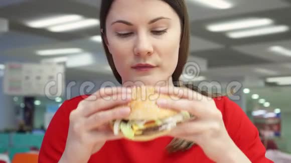 饥饿的女孩在食物场上吃汉堡包快餐店的女人咬芝士汉堡视频的预览图