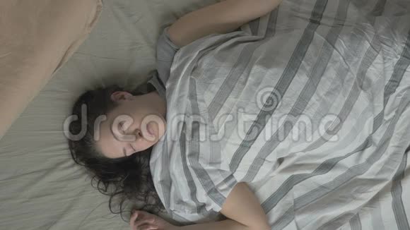 躺在床上的年轻女子早上醒来打着电话上面的景色视频的预览图