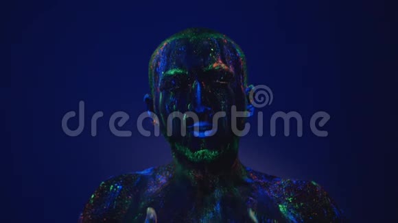 一个人在紫外线下从脸上擦荧光粉在生活环境前的空虚视频的预览图