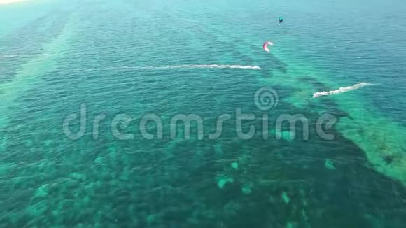 令人惊叹的4k空中无人机全景人们在晴朗的蓝色绿松石海水中放风筝在大风的夏日视频的预览图