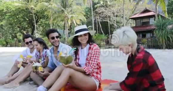人们吃热带水果喝椰子鸡尾酒坐在棕榈树上快乐的男人和女人游客品尝视频的预览图