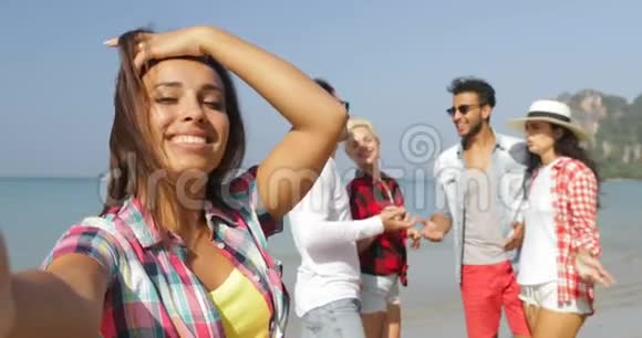 女孩欢迎人们团体在沙滩上自助拍照手机快乐度假游客视频的预览图