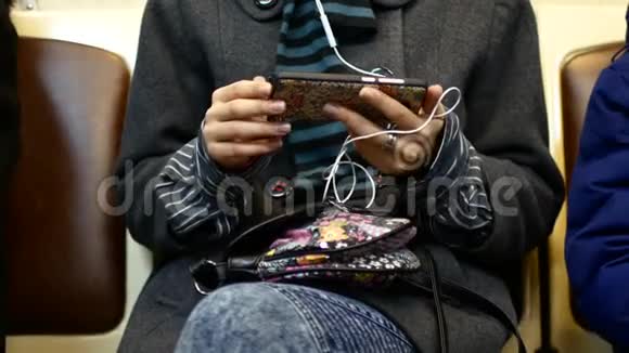 一个女孩在地铁车上听音乐或看智能手机上的视频视频的预览图