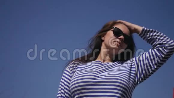 美丽的年轻女孩穿着条纹毛衣在蓝天背景下享受大自然慢动作1920x1080视频的预览图