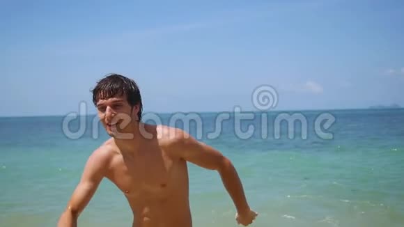 年轻英俊的快乐男人在阳光明媚的日子里从海里缓慢地奔跑1920x1080视频的预览图