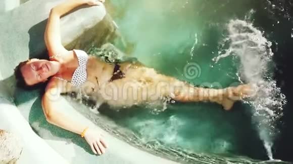 美丽的比基尼美女享受豪华水疗理疗水射流游泳池慢动作1920x1080视频的预览图