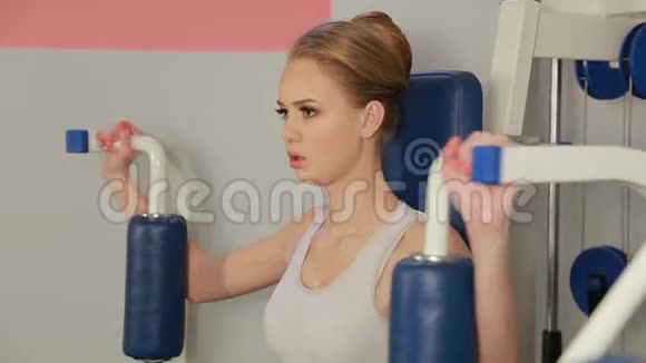 健身房健身金发白种人女人在机器上做手臂锻炼视频的预览图