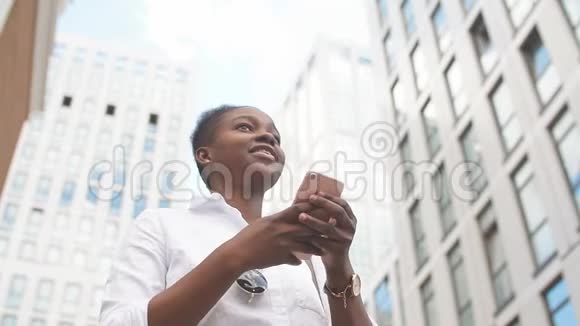 非洲妇女在户外坐在白色楼梯上使用智能手机视频的预览图
