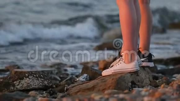 两个年轻女人的腿在岩石海岸上排成一排视频的预览图