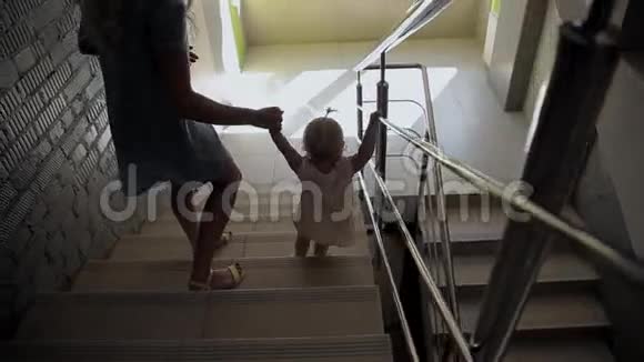 女孩和妈妈一起走楼梯黑景视频的预览图