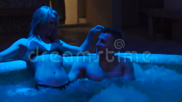 在按摩浴缸里的那对那个女人正在抚摸他的头发蓝色的灯光视频的预览图