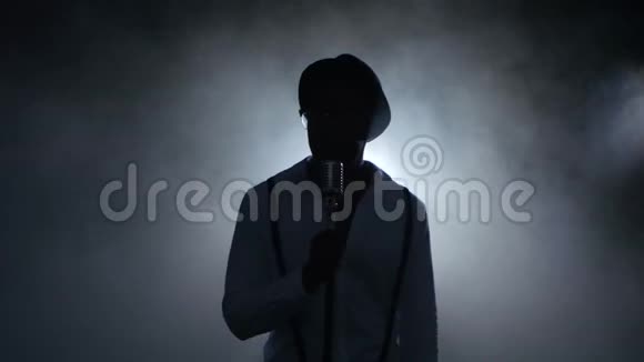 音乐家年轻的非裔美国人在烟雾和白光中唱成麦克风在录音室黑色视频的预览图