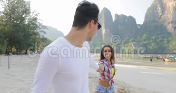 男主角情侣在沙滩上散步手牵手在度假中与年轻游客交谈视频的预览图