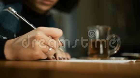 年轻女子坐在户外咖啡馆秋天裹着毯子她在文件上签名写着一支铅笔视频的预览图