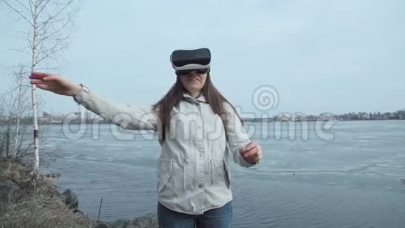 一个女人站在春天的池塘旁边用虚拟现实眼镜视频的预览图