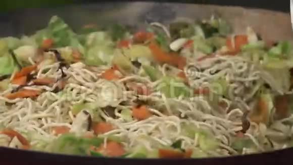炒锅里放有沙拉和胡萝卜的意大利面视频的预览图
