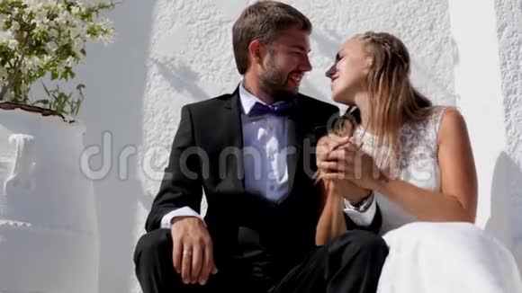 新婚快乐的新婚夫妇在他们的婚礼当天坐在他们的酒店附近视频的预览图