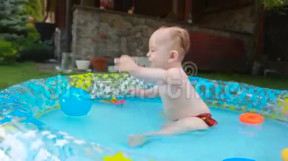 一岁的幼儿男孩在花园的充气游泳池里玩耍视频的预览图