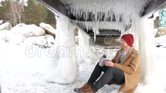 年轻的渔夫坐在湖边拿着热水瓶喝茶视频的预览图