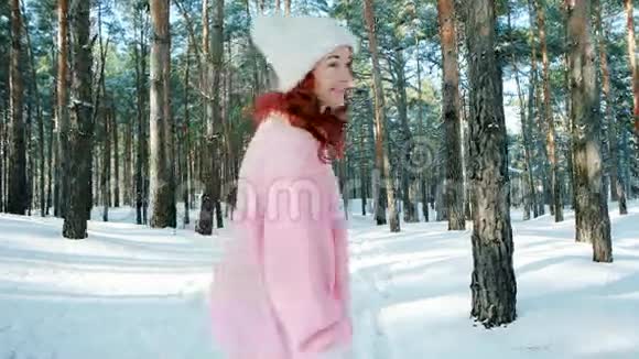温暖而快乐的冬天可爱的女孩走在森林里一个红头发的女人在雪地里跑来跑去视频的预览图