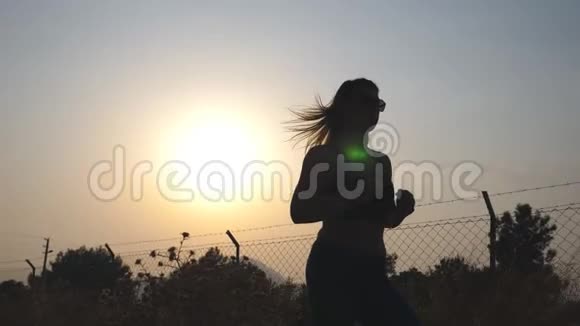 日出时在乡间小路上慢跑的运动女孩年轻女子早上在户外跑步健康活动视频的预览图