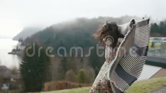 微笑的女人拿着格子在春山的背景下快乐地奔跑和旋转视频的预览图