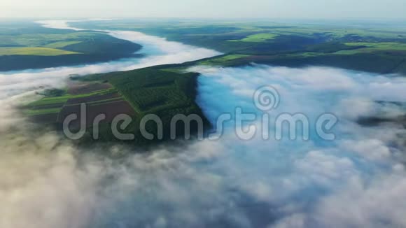 在云层上方的山上鸟瞰田野日出时鸟瞰河流上空的雾浓雾笼罩河流视频的预览图