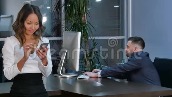 在笔记本电脑上工作的商人在办公室里使用智能手机的商人视频的预览图