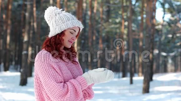 一个女孩拿着一杯茶的肖像双手戴着针织手套喝了一杯热饮料寒冷的冬天年轻的女人在街上视频的预览图