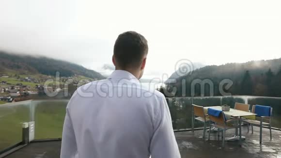 男人的后景去阳台栅栏欣赏森林和河流的景色视频的预览图