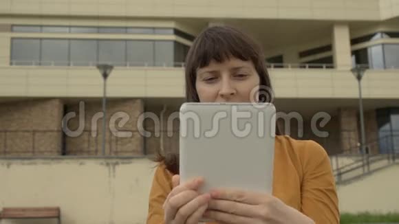 年轻女子用平板电脑站在办公楼的背景上视频的预览图