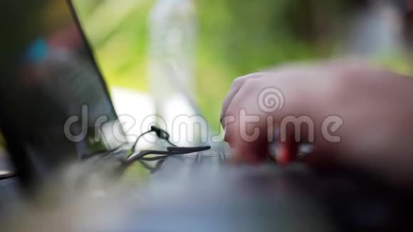 在背景模糊的自然环境下他的手在笔记本电脑上工作视频的预览图