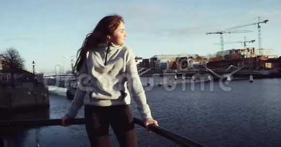 美丽微笑的黑发女孩脱下她的夹克走在桥上河的背景红色史诗4k视频的预览图