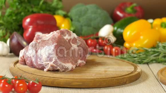厨师拿了一块生的多汁肉放在一块圆木板上背景是蔬菜青菜西兰花红色视频的预览图