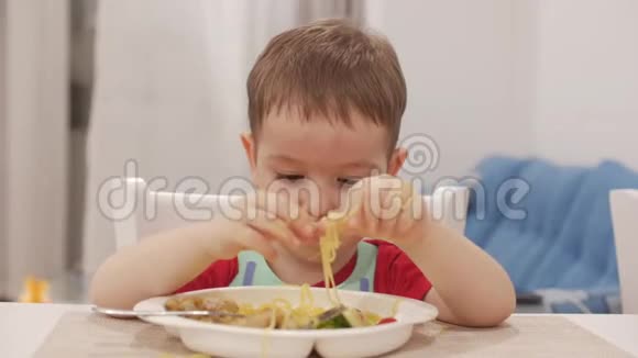 小孩子坐在一张桌子旁吃自己的意大利面可爱的小猫可爱的小宝宝视频的预览图
