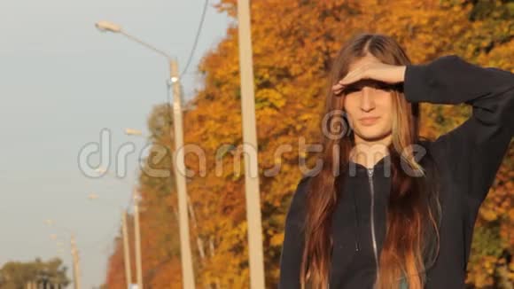 一个头戴帽子的女孩头发松松的站着手举起来搭便车秋天的森林和视频的预览图