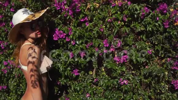 盛开的花园里戴着草帽和太阳镜的金发女郎视频的预览图