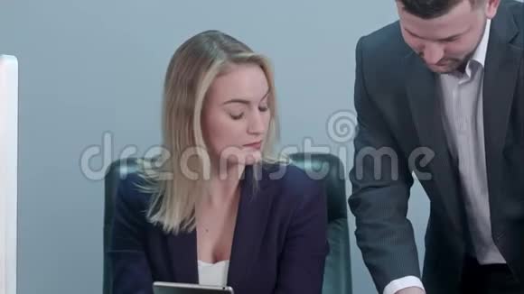 年轻的女老板坐在工作场所和白种人同事一起读论文视频的预览图
