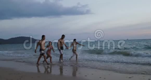 在日落时分在沙滩上散步的人群夏季度假期间的两对混合种族夫妇交流视频的预览图
