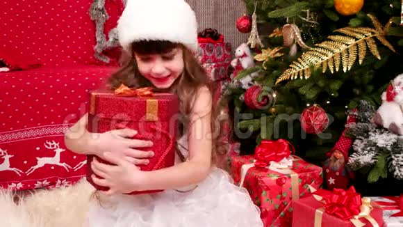 孩子喜欢圣诞节的礼物小女孩在圣诞前夜在家里玩礼物孩子狂欢节服装视频的预览图