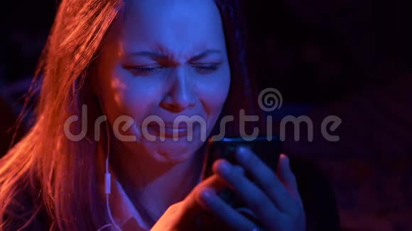 不高兴的悲伤少女在晚上与电话阅读短信很有表现力视频的预览图