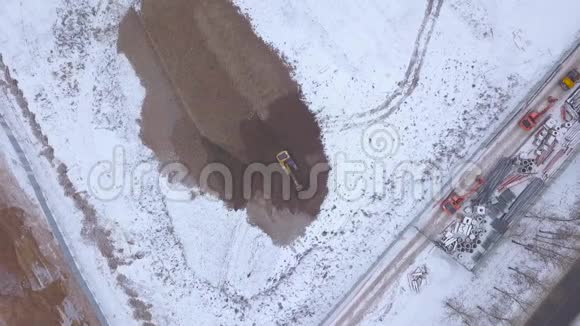 采矿挖掘机在工业区无人机视图雪地挖洞视频的预览图