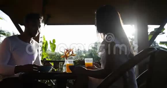 情侣在夏季露台上吃早餐男人和女人在早晨享受健康的美食户外交流视频的预览图