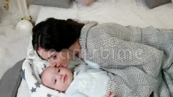 年轻的母亲和她的小儿子年轻的女人抚摸拥抱抚摸他的小儿子一家人在一个舒适的地方视频的预览图