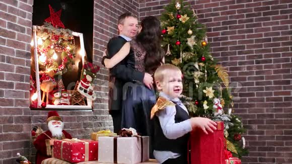 孩子玩圣诞礼物的背景情侣父母在圣诞树旁跳舞一家人幸福快乐视频的预览图