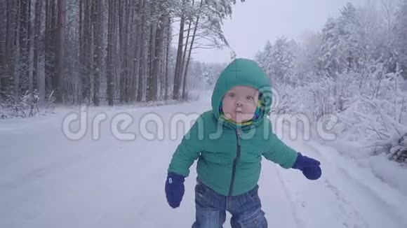 小男孩在在雪地上玩耍小男孩走在冬林里慢动作视频的预览图